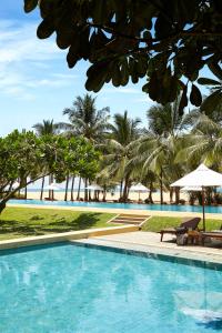a swimming pool next to a beach with palm trees at Jetwing Beach in Negombo