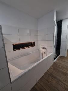 a white bath tub in a white tiled bathroom at Apartmán Jana in Vysoké Mýto +5 photos