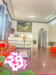 Una sala de estar con un sofá y una mesa con flores. en Dona Hotel, en Da Lat