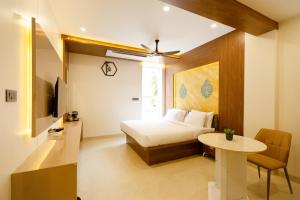 um quarto com uma cama, uma mesa e uma TV em Kaizen Residency Trichy em Tiruchchirappalli