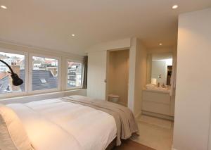 een slaapkamer met een groot wit bed en een raam bij Studio Ocean by BLOSS, luxe studio in Knokke in Knokke-Heist