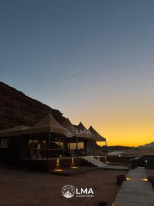 ワディ・ラムにあるLMA Rum Luxury Campの夕日を背景にしたテントのある建物