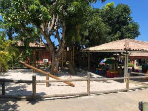 une aire de jeux en face d'une maison avec un arbre dans l'établissement Chalé das flores, à Maceió