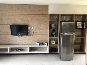 a kitchen with a refrigerator and a tv at Chalé das flores in Maceió +7 photos