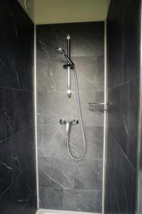a shower in a bathroom with black tiles at Logis Hotel Spa Restaurant Au Site Normand in Clécy +51 photos