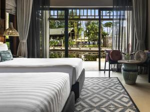 a hotel room with a bed and a large window at Grand Mercure Khao Lak Bangsak in Khao Lak
