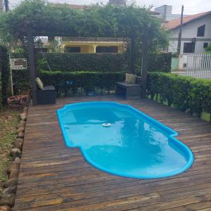 a blue swimming pool on a wooden deck at Pousada da Nega in Barra Velha