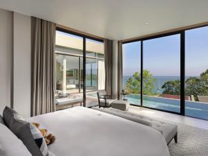 a bedroom with a large bed and a large window at V Villas Phuket - MGallery Collection in Panwa Beach