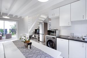 a kitchen with white cabinets and a washer at Chive Cottage in Cape St Francis