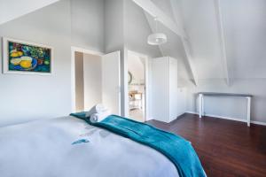 a white bedroom with a bed with a blue blanket on it at Chive Cottage in Cape St Francis +27 photos