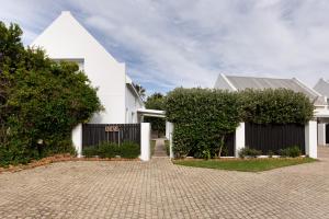 a white house with a brick driveway at Chive Cottage in Cape St Francis