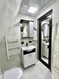 ein weißes Badezimmer mit Waschbecken und Spiegel in der Unterkunft Cozy wooden cottage in the forest 2 km from Kutais in Kutaissi