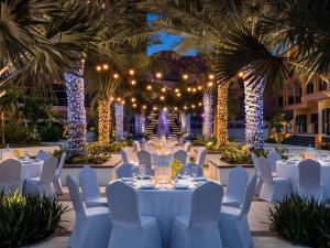 a wedding reception with white tables and chairs and lights at Fairmont Fujairah Beach Resort in Al Aqah +130 photos