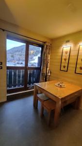 Zimmer mit einem Holztisch und einem großen Fenster in der Unterkunft Gentianes 6 in La Norma