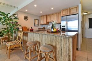 a kitchen with a counter with stools and a refrigerator at Kaleialoha 211 · KA 211 OceanFront 1BD Whale Watch Relax Getaway in Kahana