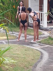 Dos mujeres paradas afuera de una casa, de espaldas. en The Blue Lagoon Villas, en Nusa Ceningan