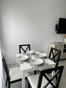 a white dining room table with white plates and chairs at Apartamento Deluxe 1 Room Piscina Parking LuxSevilla Bormujos in Bormujos