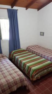 two beds in a room with blue curtains at Casaquinta en Paso con Pileta y Parrilla in Paso de la Patria