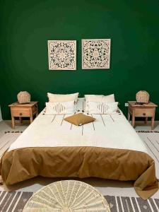 a bedroom with a large bed with a green wall at Dar Naifer in Tozeur