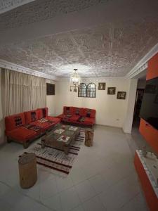 a living room with red couches and a table at Dar Naifer in Tozeur