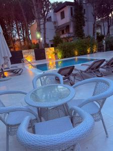 a glass table and chairs next to a swimming pool at Swiss Villa Qerret in Golem