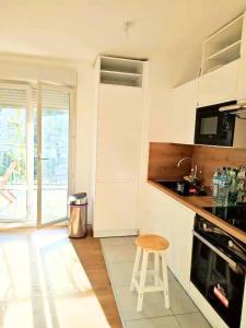 a kitchen with a stool in front of a stove at Face au Métro 14, Chambre avec balcon et vue sur jardin, 5 min Orly, 7 min Paris in Chevilly-Larue