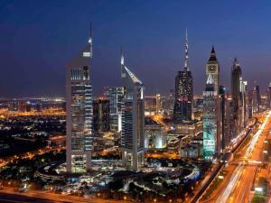 ドバイにあるSwissôtel Al Murooj Dubaiの時計塔のある夜の街並み