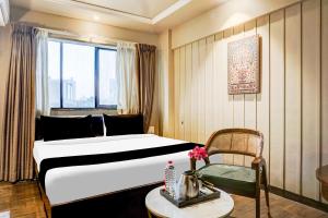 una habitación de hotel con una cama y una silla en Collection O Viman Nagar Downtown Formerly Hotel Cilantro, en Pune