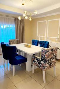 ein Esszimmer mit einem weißen Tisch und blauen Stühlen in der Unterkunft Sunrise Serenity Lux Homes in Lilongwe