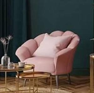 a pink chair in a living room with a table at Unit with bed in Busy Osu in Accra