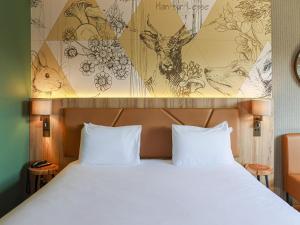 a bed with two white pillows in a room at Mercure Han-sur-Lesse in Han-sur-Lesse