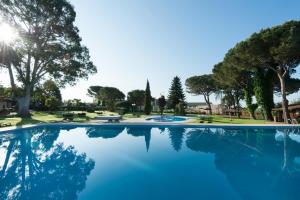 a large swimming pool with trees and blue water at Hotel Mas Solà in Santa Coloma de Farners