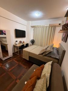 ein Schlafzimmer mit einem Bett, einer Couch und einem Schreibtisch in der Unterkunft Estúdio 9º andar em frente à Praça da República in Belém