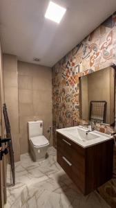 a bathroom with a toilet and a sink and a mirror at RR ApartHotel in Ouarzazate