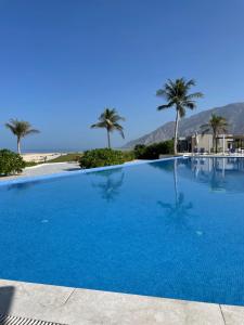 a large blue swimming pool with palm trees in the background at Sunrise Haven in As Sīfah