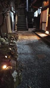 a building with stairs and a stone wall with lights at 古民家ふるさと真鶴 in Wada