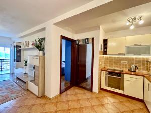 a kitchen with white cabinets and a tile floor at Sea View Budva in Budva +20 photos