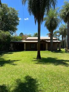 a house with a palm tree in the yard at Lujoso Chalé frente al Río con Piscina in Paso de la Patria