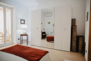 Habitación blanca con espejo y cama en La casa del sole, en Molfetta