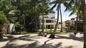 a white house with palm trees in front of it at Jardim Azul Praia in Pitimbu