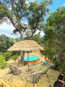a table and chairs under a straw umbrella on a deck at ōku in Monchique