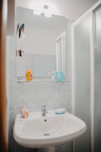 Un baño con un lavabo blanco y un espejo. en La casa del sole, en Molfetta