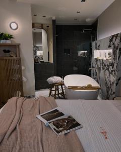 a bathroom with a tub and a bed with a magazine on it at City Core Katerini, Platea Lux in Katerini