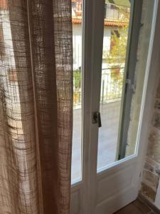 an open door with a window with curtains at Stone House Bourgos in Koroni