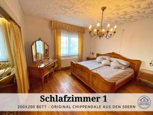 1 dormitorio con cama, espejo y lámpara de araña en Apartment Rosie - Rustikal und top ausgestattet und ideal für Gruppen bis 6 Personen und Hund, egal ob Familie, Kollegen oder Freunde, 85qm mit Garten und eigener Garage, en Riegelsberg