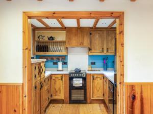 a kitchen with wooden cabinets and a stove at Seaton Cottage - Uk31990 in Staithes