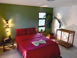 a bedroom with a red bed and a green wall at Jardim Azul Praia in Pitimbu
