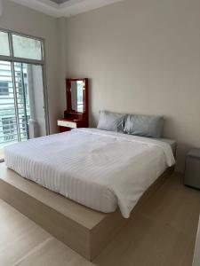 een groot wit bed in een slaapkamer met een raam bij Kami Guest House Patong in Patong Beach