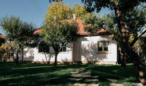 a white house with trees in front of it at Stone House in Tîrgu Secuiesc