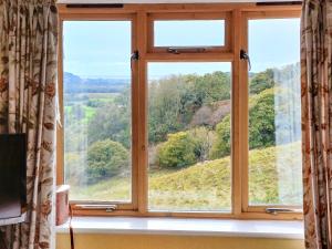 a window with a view of a hill seen through it at Erw Goed Old Barn in Arthog